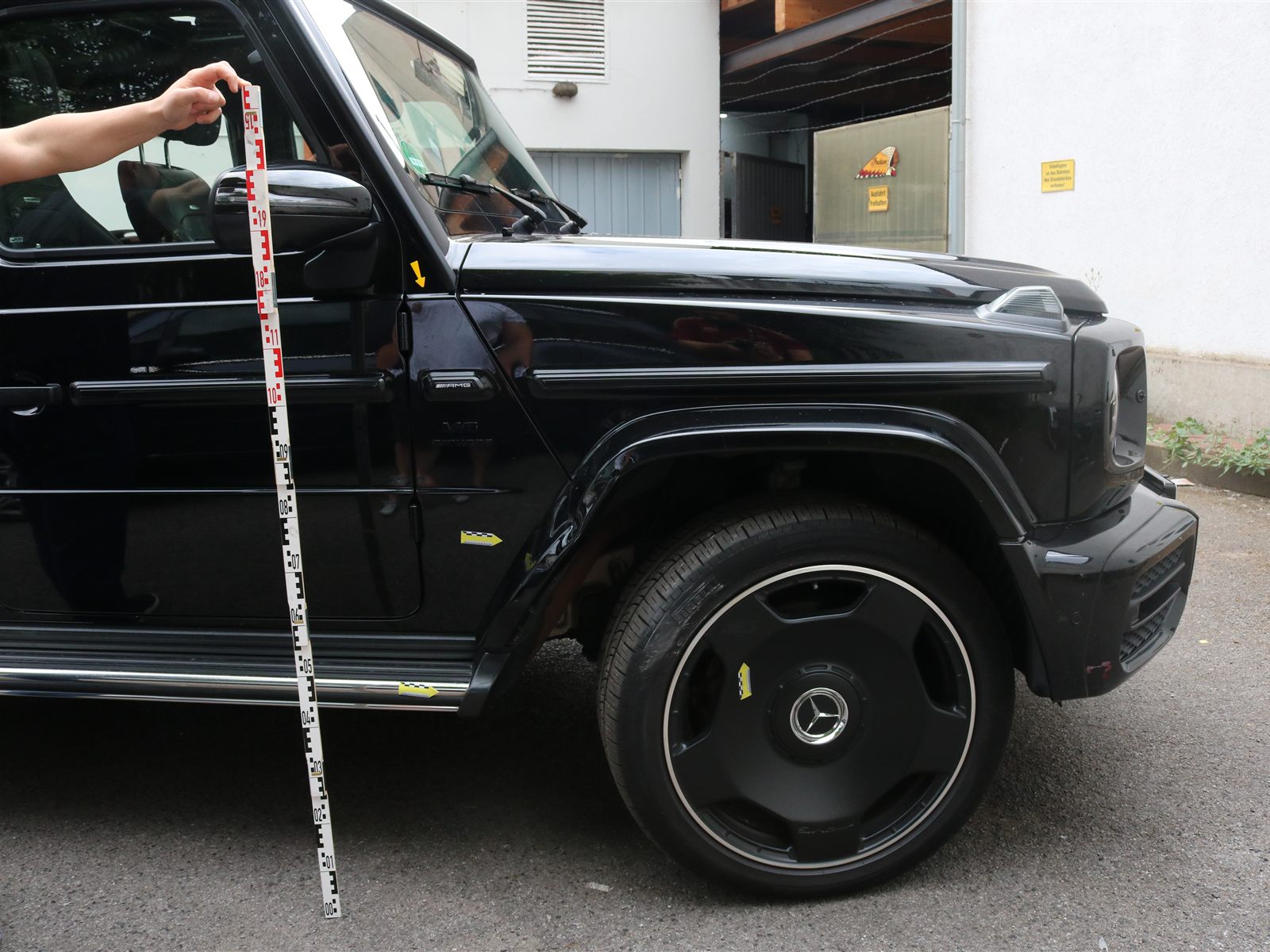 Schadenaufnahme mit Messlatte an einem schwarzen Mercedes-AMG G 63